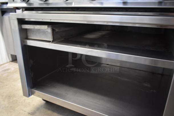 Stainless steel commercial oven, open compartment, slight wear, suitable for industrial kitchen use.