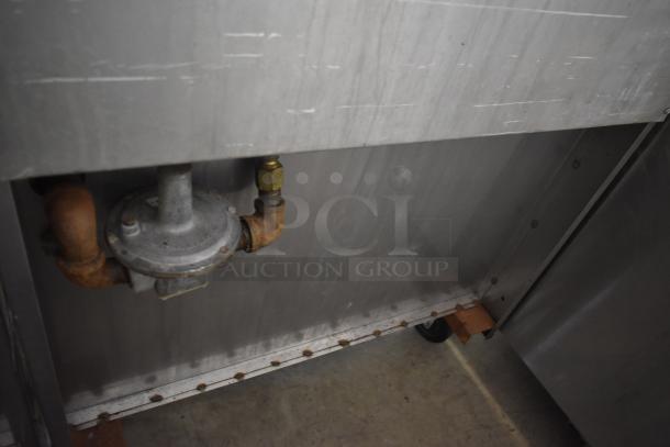 Industrial gas regulator with copper pipes attached to stainless steel equipment. Rust and wear visible on pipes.