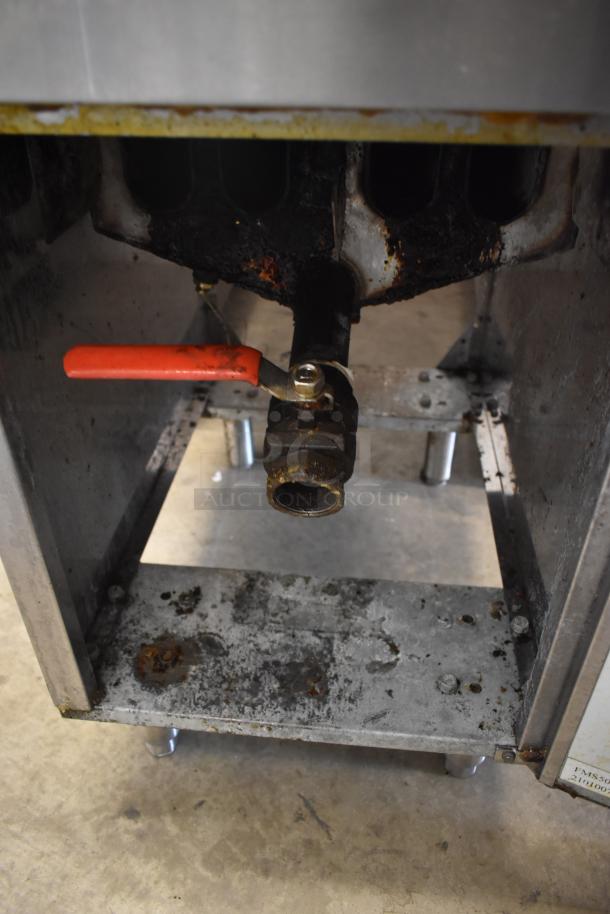 Commercial gas appliance with a rusted valve and red handle, showing signs of heavy wear and corrosion.