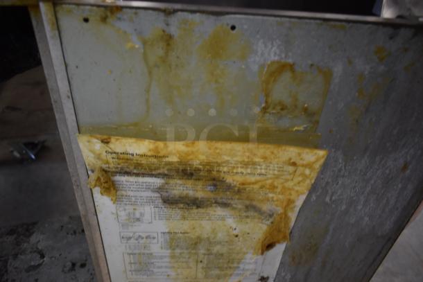 Metal panel with rust and residue, featuring a weathered operating instructions label, partially legible.