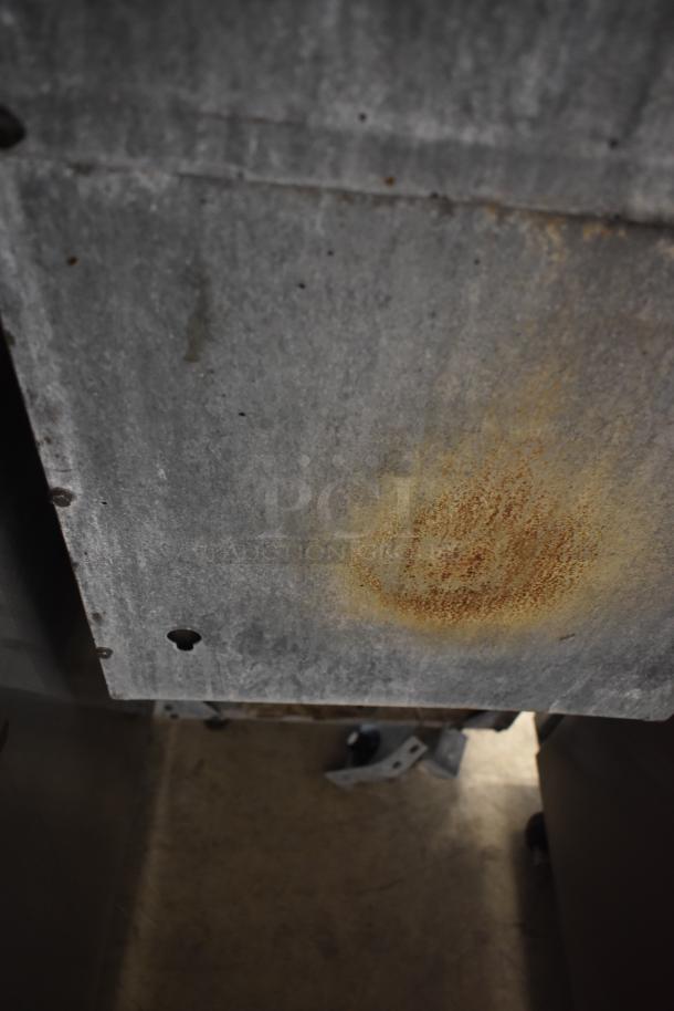 Rusty metal panel with surface corrosion, showing signs of wear and aging. No visible tags or markings.