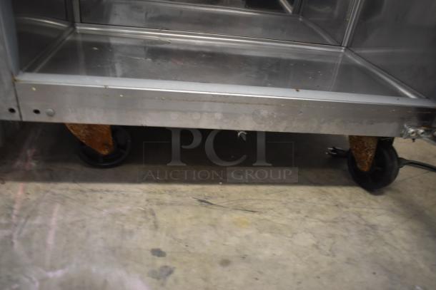 Stainless steel cart on wheels; used condition with rust on casters; ideal for kitchen or industrial use.