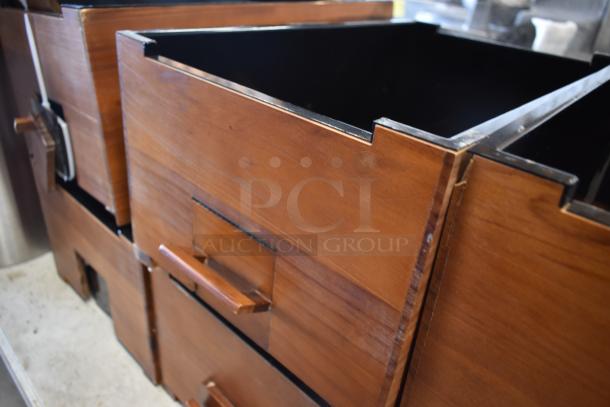 Wooden stacking file drawers with metal trim, showing wear. Each drawer features a rectangular handle and dovetail joints.