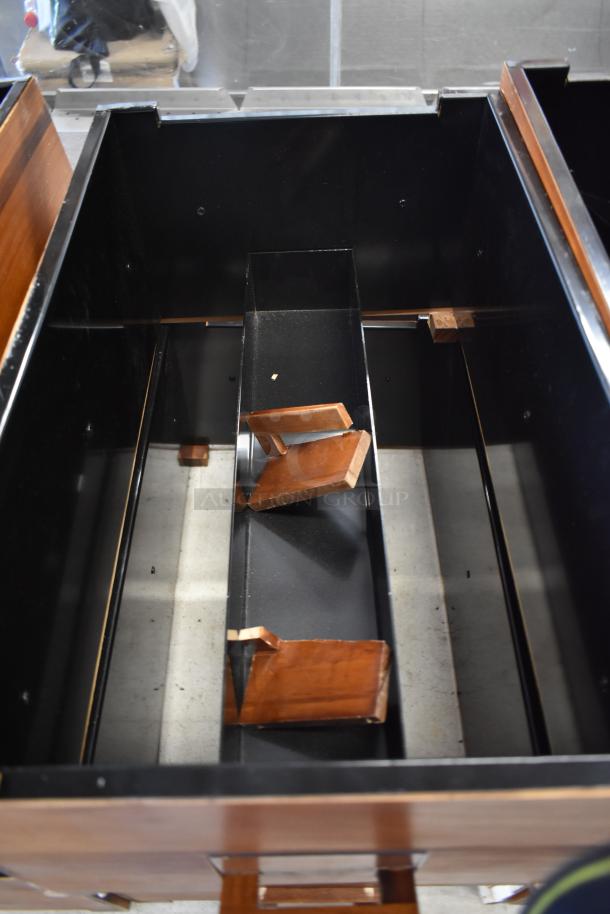 Wooden cabinet interior with black metal components and adjustable shelves, showing minor wear.