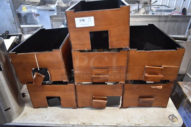 Stack of brown wooden storage boxes with cut-out handles and a label indicating "QTY 7". Slight wear visible.
