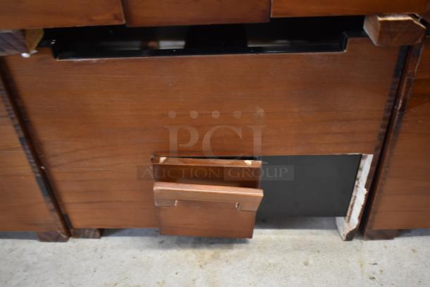 Wooden furniture piece with sliding compartment, showing wear. Rich brown finish and visible corner construction details.