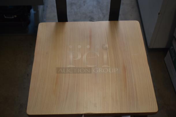 Wooden chair seat with visible grain, minor scratches, good condition. Black vertical supports visible in background.