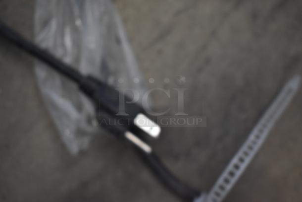 Blurred image of a black power cord with a visible plug. Condition and details unclear.