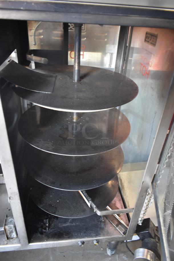 Commercial rotisserie oven with multiple black metal racks, visible wear, and “Caution: Hot” label on glass door.