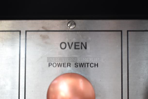 Metal oven power switch panel with "OVEN" and "POWER SWITCH" labels. Some visible wear and screw at top center.