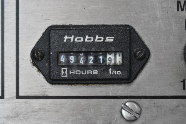Vintage Hobbs hour meter showing 4921.9 hours, mounted on metallic surface, in used condition with minor wear.