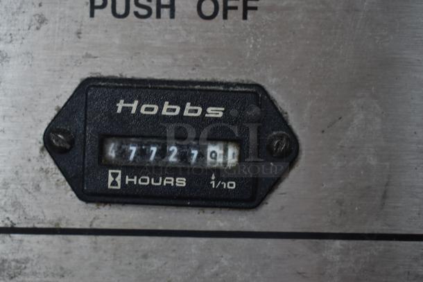 Hobbs hour meter reading 7727.9 hours, used condition, black frame, mounted on a metal surface with "Push Off" label visible.