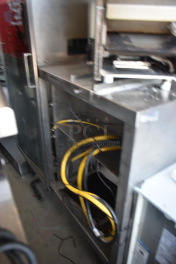 Commercial kitchen equipment with stainless steel casing and visible yellow cables, showing wear. No visible labels.