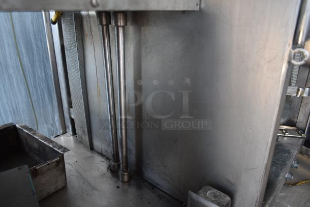 Industrial metal machinery with rods and clamps, stainless steel, showing signs of wear. No visible tags or markings.