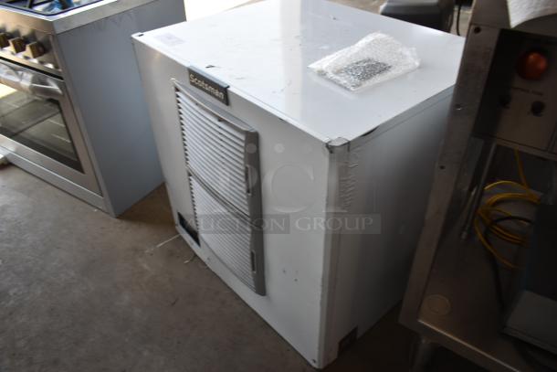 Scotsman commercial ice maker, white, dual door, visible wear on surface, includes bubble-wrapped accessories on top.