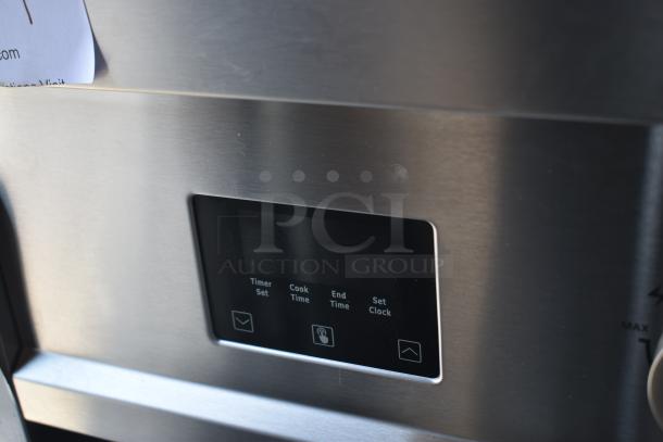 Close-up of a stainless steel oven control panel with digital display, showing options for timer set, cook time, and clock settings.