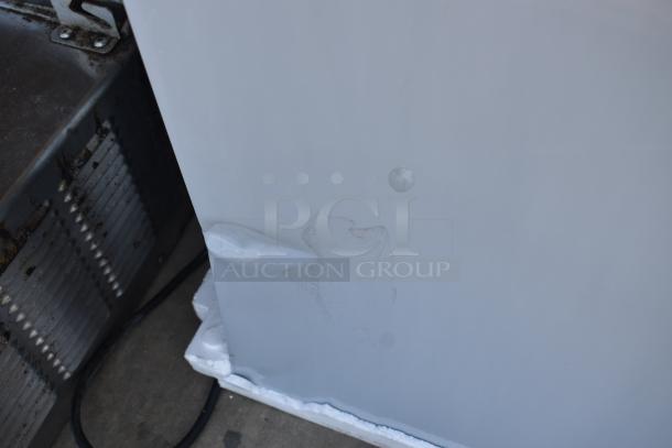 White appliance with visible dents and marks on the side, indicating moderate wear. No tags or labels visible.