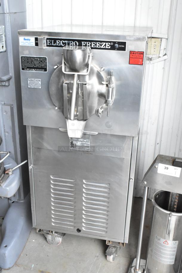 Electro Freeze FT-1 stainless steel batch freezer on commercial casters, 230V, 1 phase, showing front operational controls and caution labels.