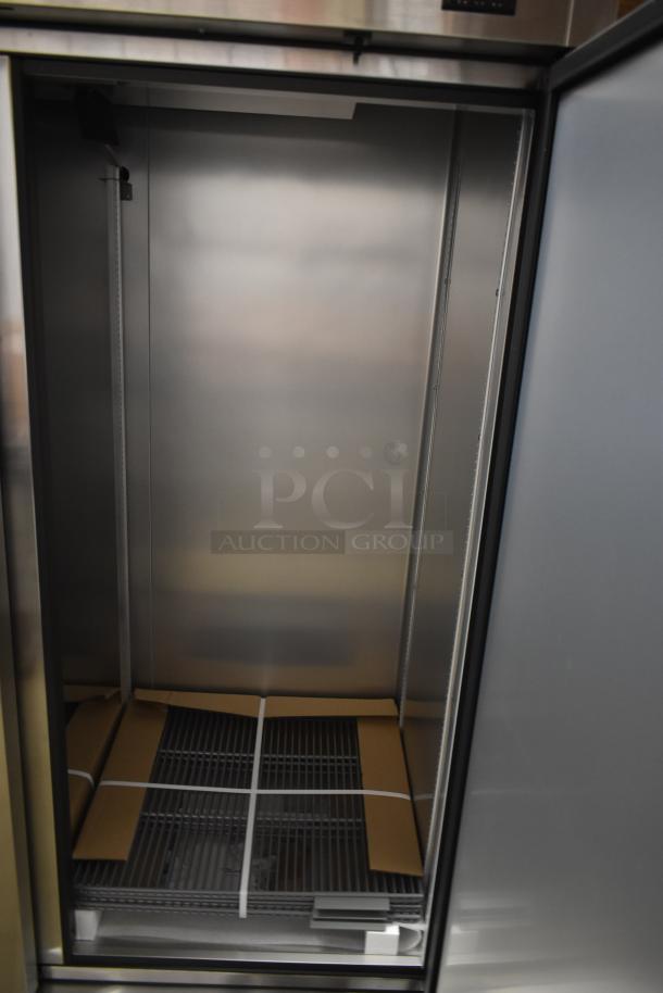 Stainless steel commercial refrigerator, open door, unassembled shelves inside, new condition.
