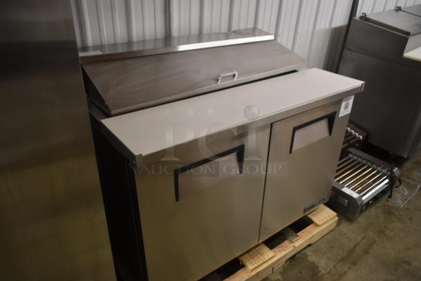 Stainless steel commercial refrigerator with two doors and worktop. Clean surface. QR label on side. Good condition.