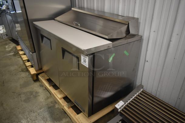 Stainless steel commercial kitchen refrigerator, two doors, top prep counter, good condition, label with QR code.