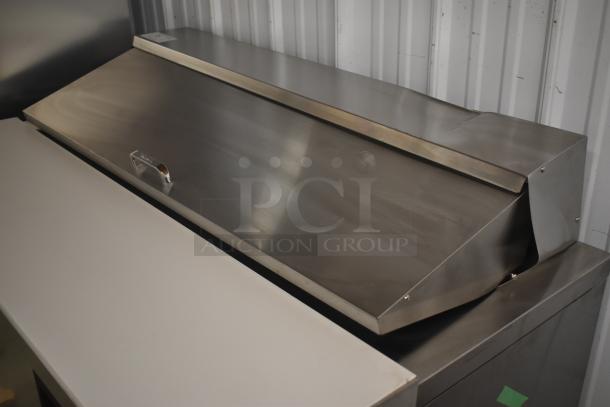 Stainless steel commercial refrigerator with a closed lid, handle, and minor surface marks. Suitable for catering.