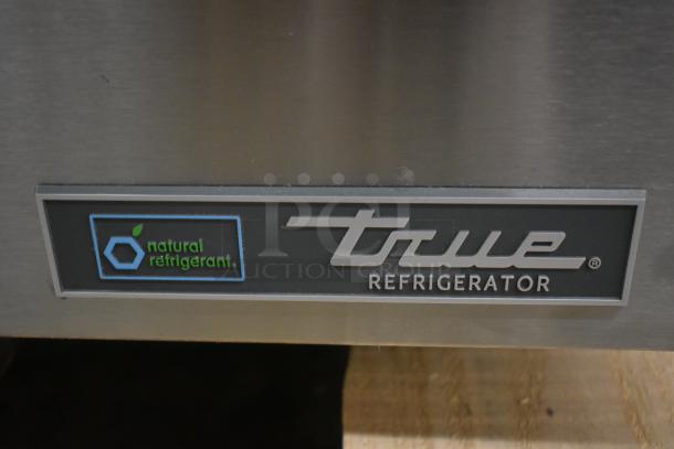 True Refrigerator label, featuring "natural refrigerant" logo. Stainless steel finish, indicating eco-friendly cooling.