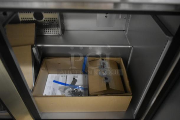 Box containing installation hardware and instructions inside a stainless steel cabinet. Appears new, unopened.