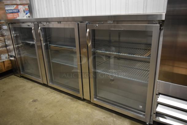 Three-door stainless steel commercial refrigerator with glass front, adjustable shelves, and locking handles. Excellent condition.