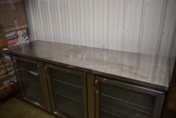 Stainless steel commercial refrigerator with three glass doors and internal shelving, in good condition, ideal for restaurant use.