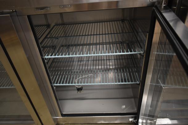 Stainless steel commercial refrigerator with glass door; interior features multiple wire shelves; keys hanging inside.