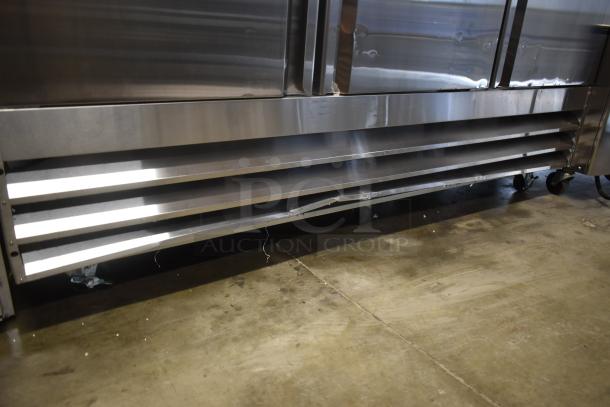 Commercial stainless steel refrigerator, lower vent panel with visible dent, on wheels. Suitable for professional kitchens.