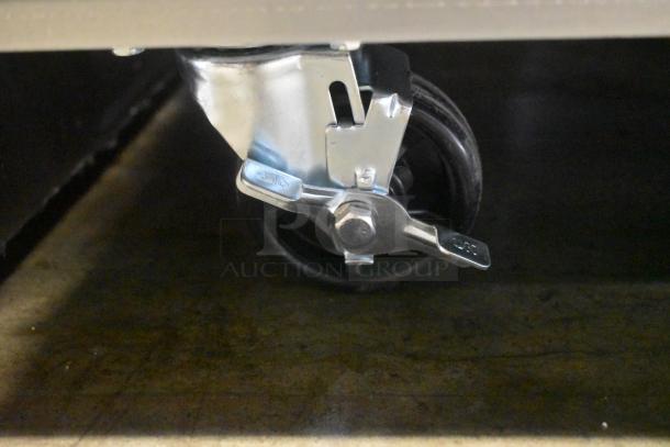 Metal swivel caster wheel with brake, shiny finish, like new condition. Suitable for industrial carts or furniture.