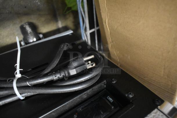 Power cord bundled with plastic tie on a black device. Visible label reads "CAREL." Device appears in good condition.
