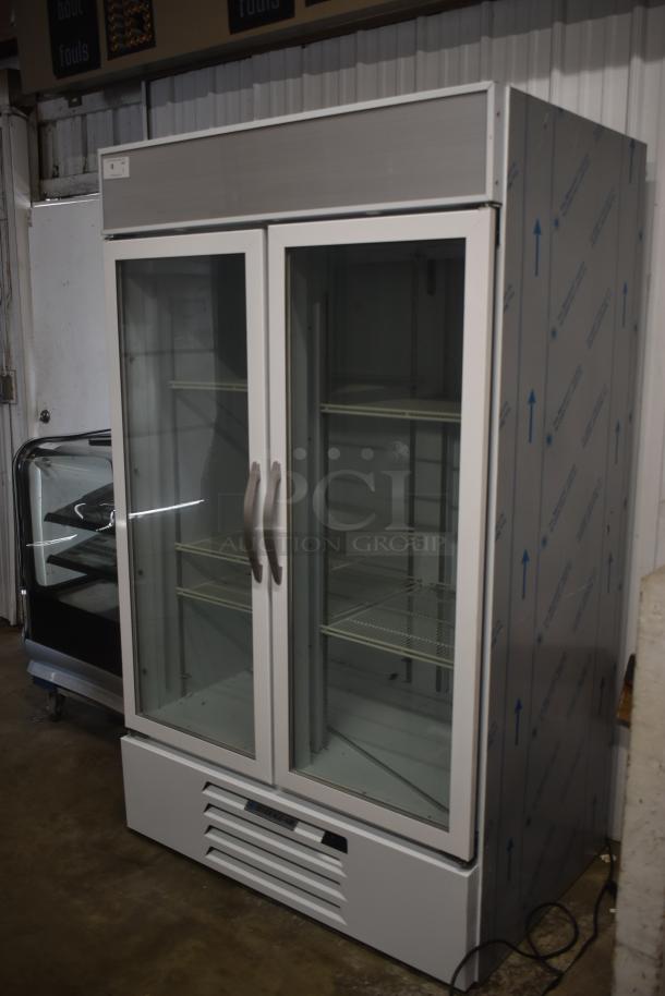 Commercial double-door refrigerator, white with glass doors, metal shelving inside, side protective film, clean condition.