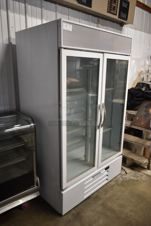 Commercial refrigerator with glass double doors, white exterior, adjustable shelves, and visible brand label. Good condition.