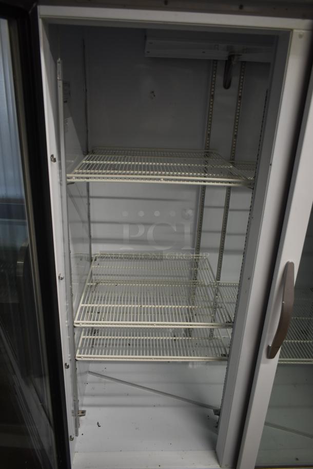 Commercial beverage cooler with two metal shelves, glass door, and visible interior wear. Ideal for display use.