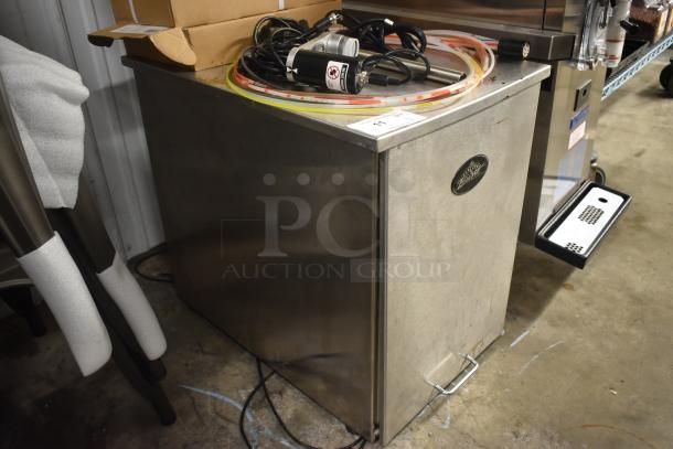 Stainless steel beverage cooler with brand label, power cords, and coiled tubing on top. Moderate wear visible.
