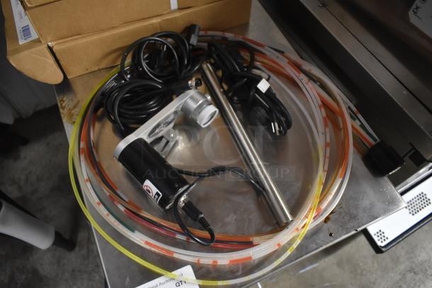 Industrial pump with colorful tubing and power cables on a metal surface. Appears unused with intact packaging nearby.