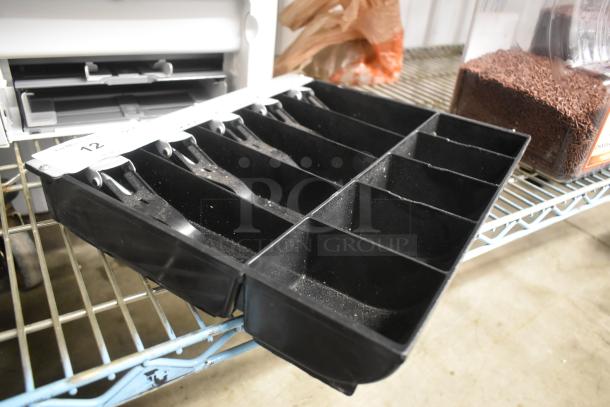 Black plastic cash register tray with multiple coin and bill compartments, slight wear, labeled with "12".