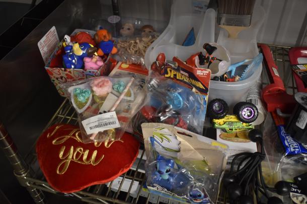 Assorted toy collection including Marvel Spiderman toy, plush heart with "I love you" text, and Disney Stitch figures in packaging.