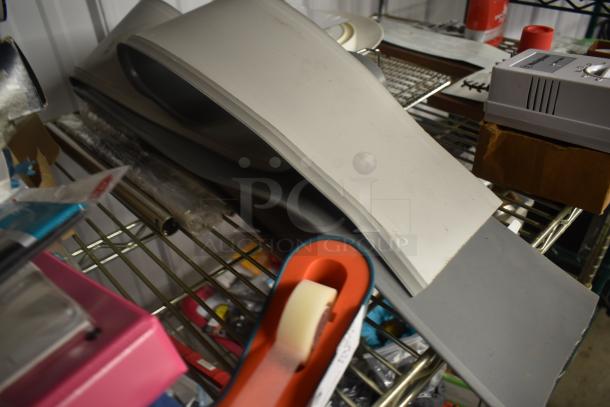 Assorted crafting tools and materials on metal shelves, including cutting mats and a tape dispenser. Mixed condition.
