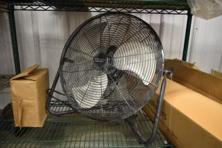 Commercial Electric floor fan, heavy-duty metal construction, silver blades, black frame, with attached pull chain on a shelf.