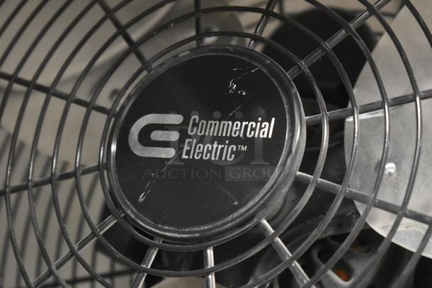 Commercial Electric fan with visible logo, black cage design, used condition with slight surface scratches on the center.