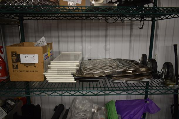 Stack of white trays, metal racks, and baking sheets on a metal shelf. Box labeled "City Electric Supply" with lot number 20.