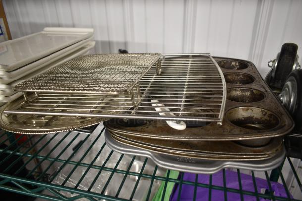Stacked baking tools including muffin tins, grill rack, and trays on a green metal shelf. Items show wear.