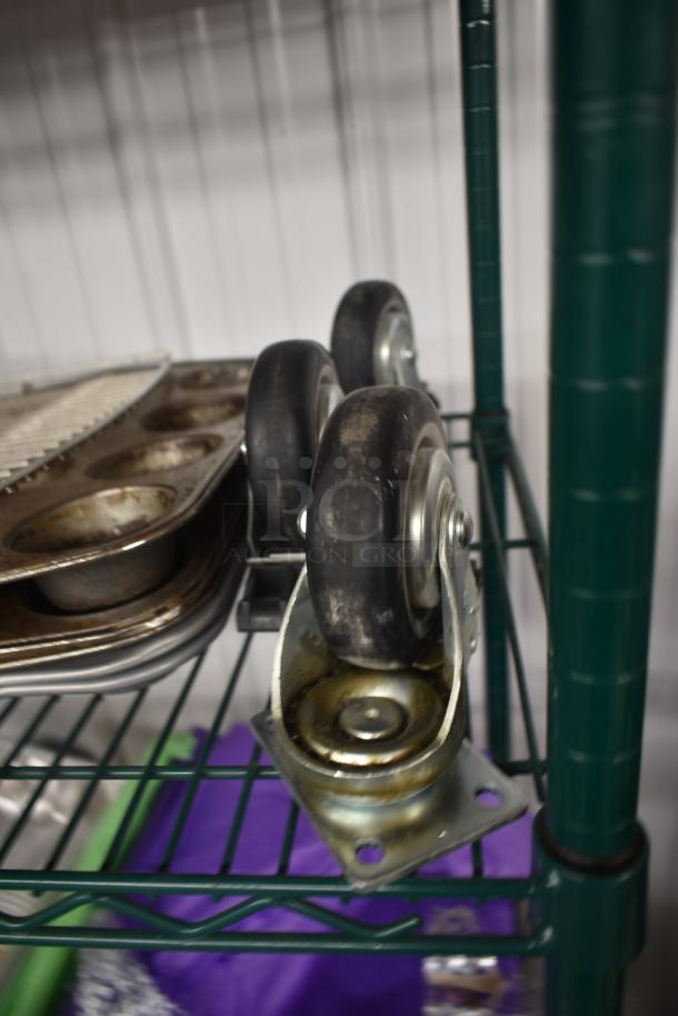 Heavy-duty caster wheels on metal shelf, used condition, alongside assorted metal baking trays.