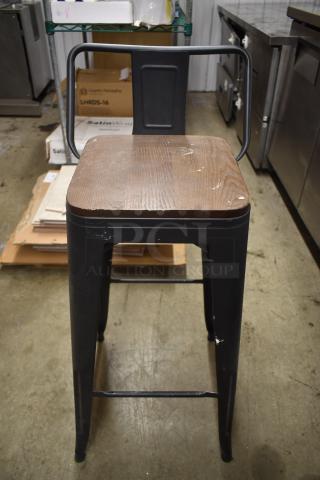 Industrial-style metal bar stool with wooden seat, black frame, scuffs and signs of wear, sturdy design, 30" height.