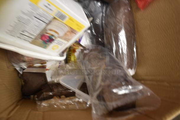 Box containing various food items, including sealed packages and containers, with visible nutritional labels.