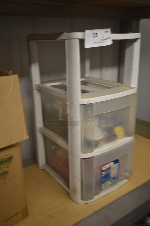 White plastic storage drawer unit with three translucent drawers containing mixed items. Auction tag with number 25 attached. Moderate wear.